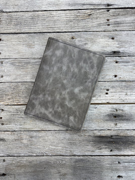 Grey oil tanned leather composition notebook cover with natural pull-up variation and black stitching.