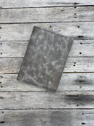 Grey oil tanned leather composition notebook cover with natural pull-up variation and black stitching.