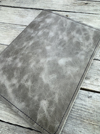 Grey oil tanned leather composition notebook cover with natural pull-up variation and black stitching.