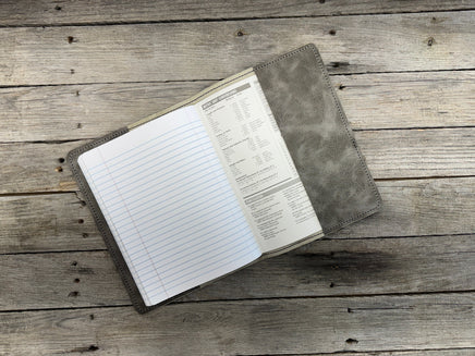 Open notebook with lined pages inside a leather-bound cover on a wooden surface
