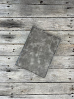 Grey oil tanned leather composition notebook cover with natural pull-up variation and black stitching.