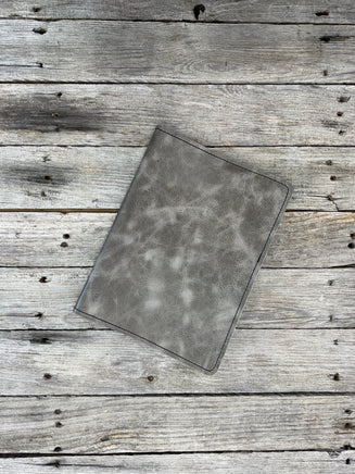 Grey oil tanned leather composition notebook cover with natural pull-up variation and black stitching.