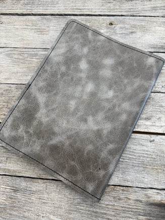 Grey oil tanned leather composition notebook cover with natural pull-up variation and black stitching.