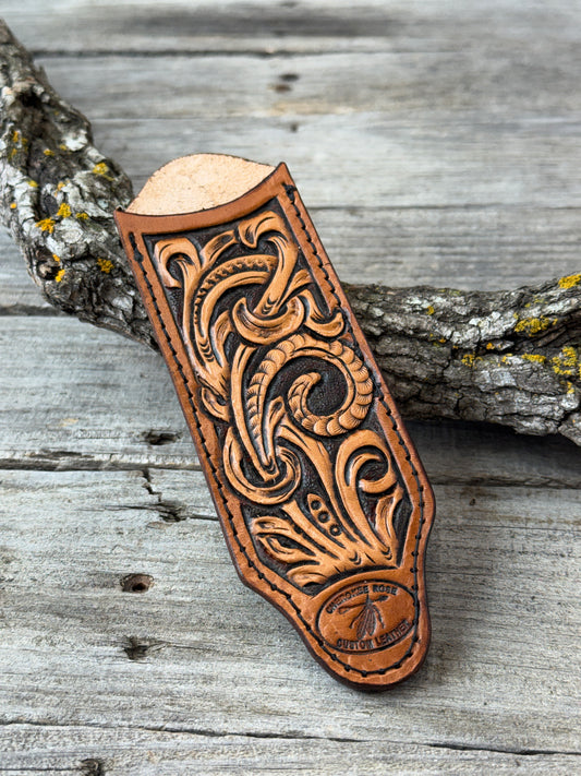 Carved leather cast iron skillet handle cover with intricate patterns on a wooden background