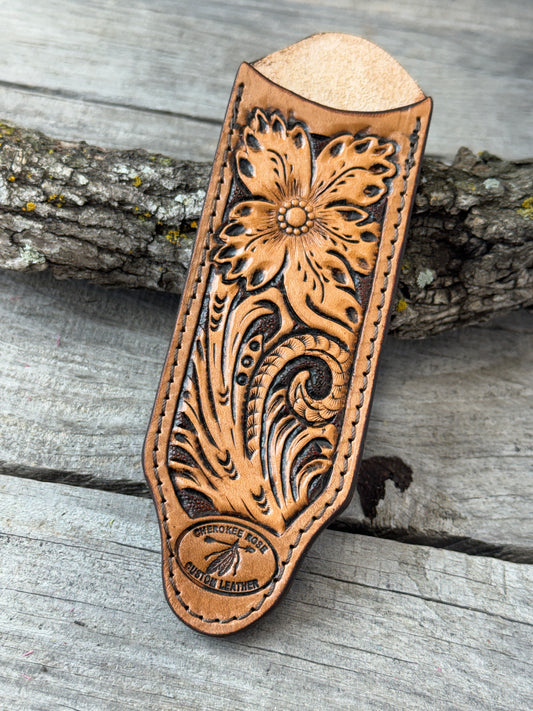 Custom hand tooled leather cast iron skillet handle cover with floral patterns on a wooden surface