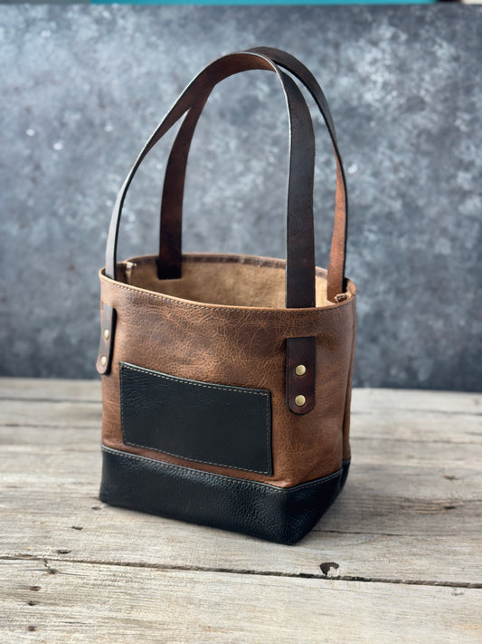 Mini two-tone bison leather tote in vintage sand and black with exterior pocket and brown leather straps