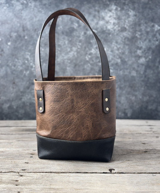 Back of mini bison leather tote showing natural vintage sand grain and black pebbled leather base