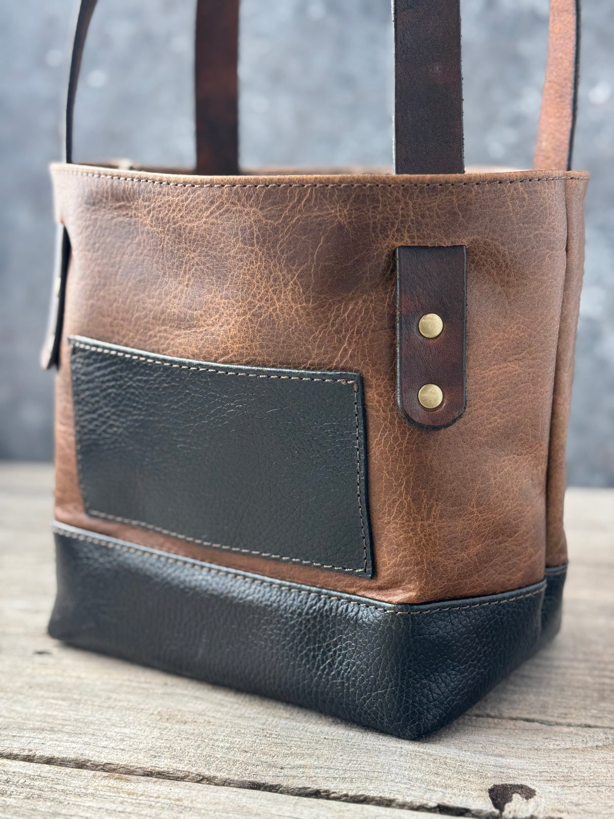 Close-up of functional black exterior pocket and antique brass rivets on vintage sand bison tote