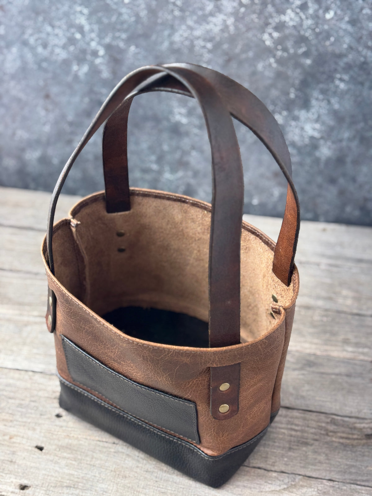 Angled overhead view of mini bison leather tote with open top and hand-dyed leather straps
