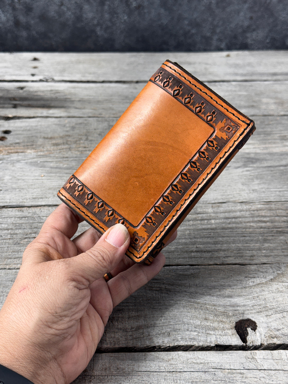 Hand stamped geometric border on brown leather trifold wallet