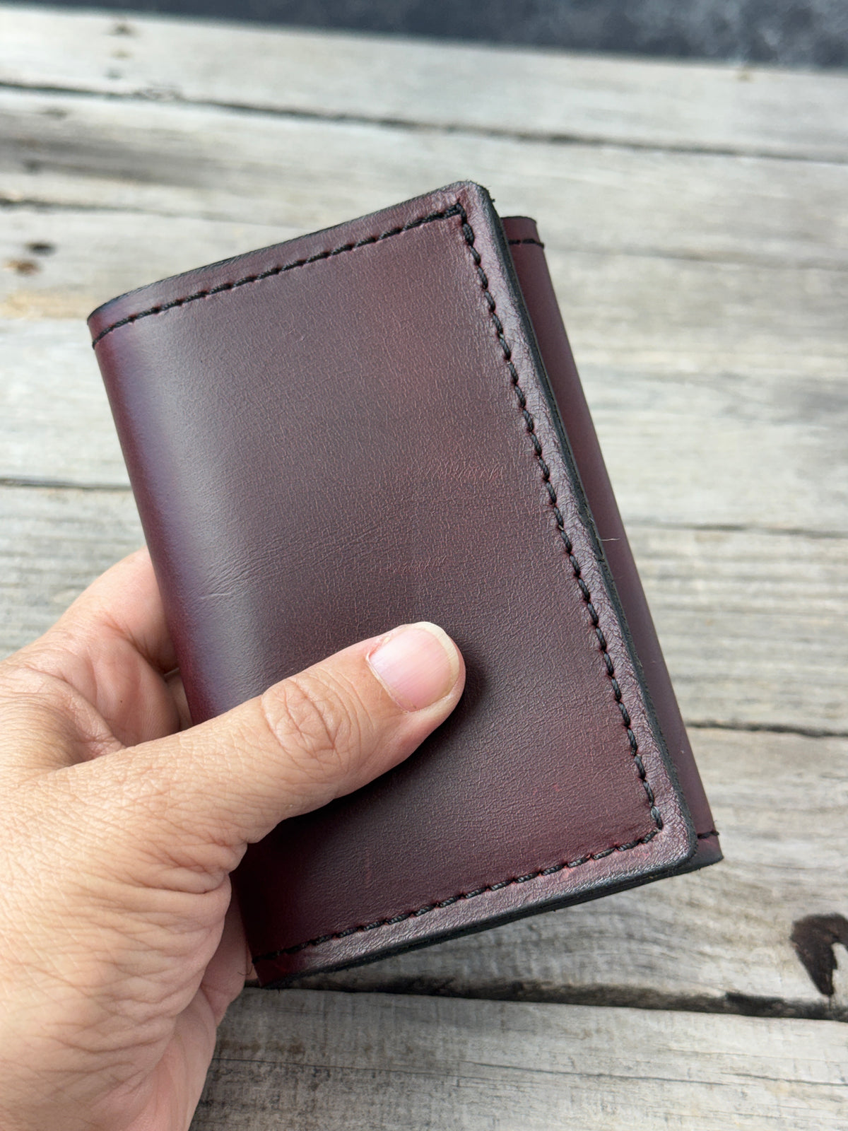 Bayou Red Brown oil tanned leather trifold wallet held in hand