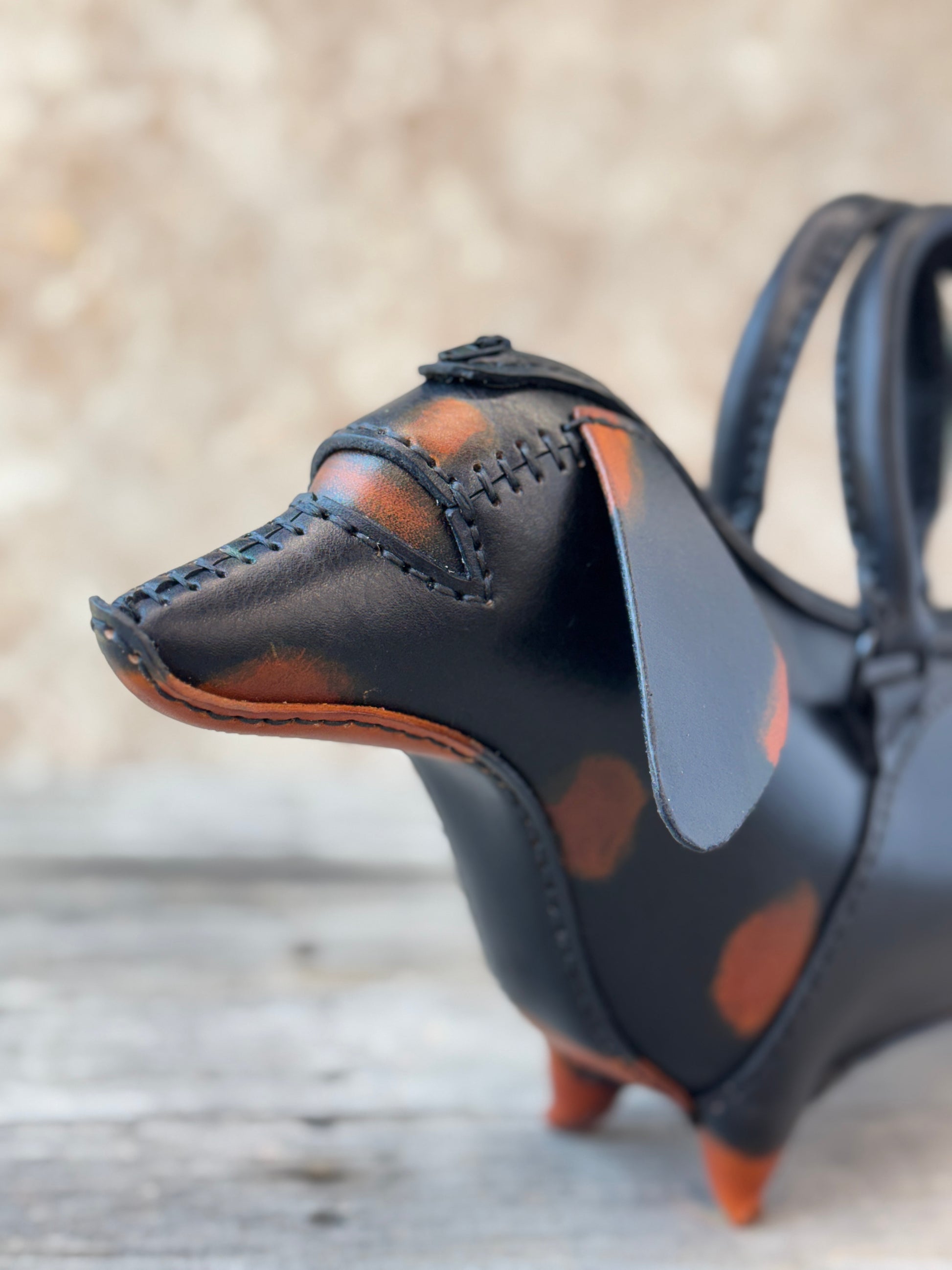 Close-up of black and tan leather dachshund purse showing hand stitched muzzle and floppy ear