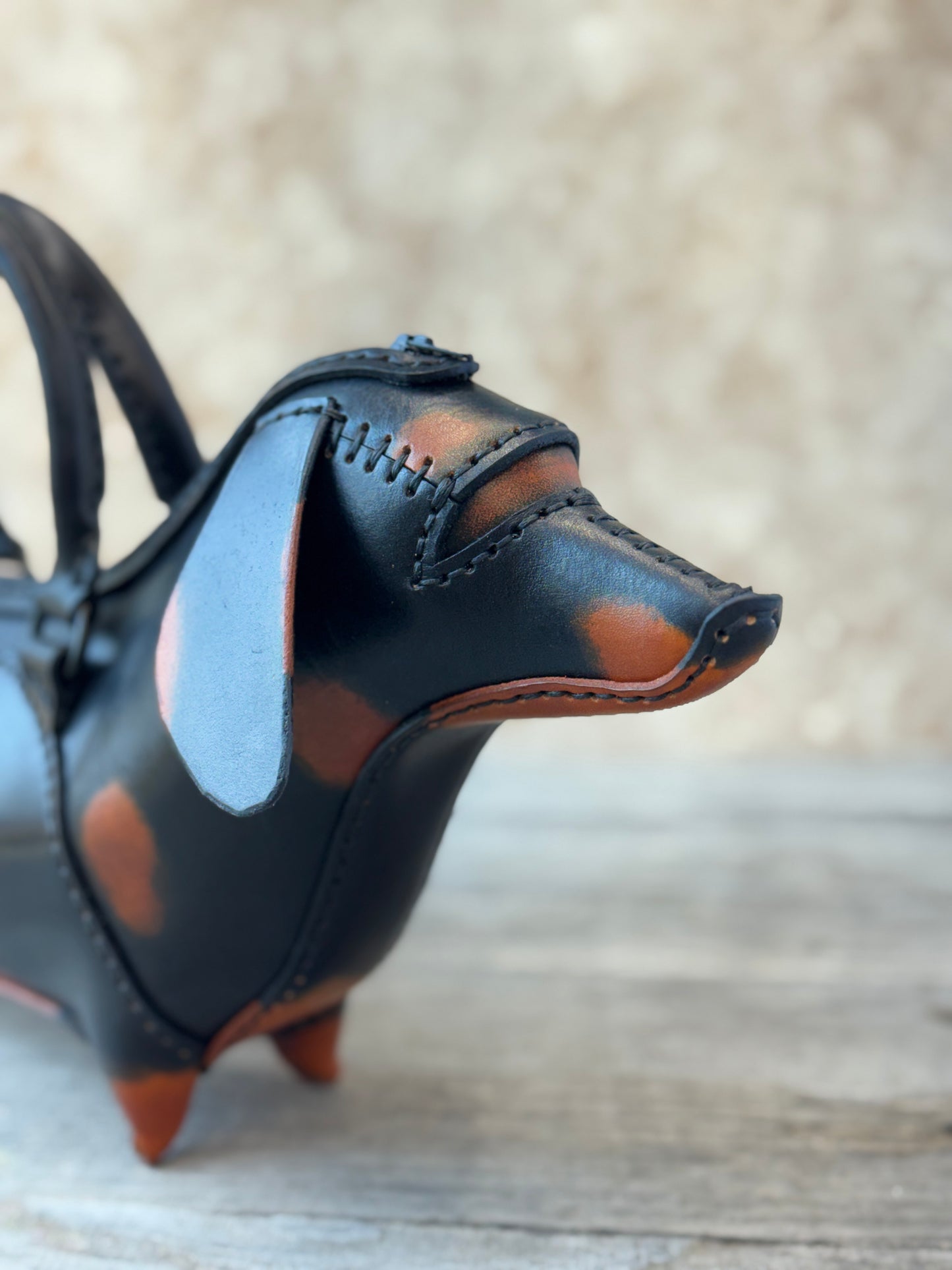 Close-up of black and tan leather dachshund purse showing hand stitched muzzle and floppy ear