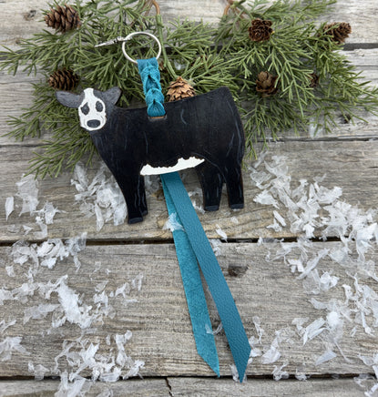 Hand-painted black and white leather show heifer purse hanger (“panda cow”) with turquoise suede strap, handmade by Cherokee Rose Custom Leather in Texas.