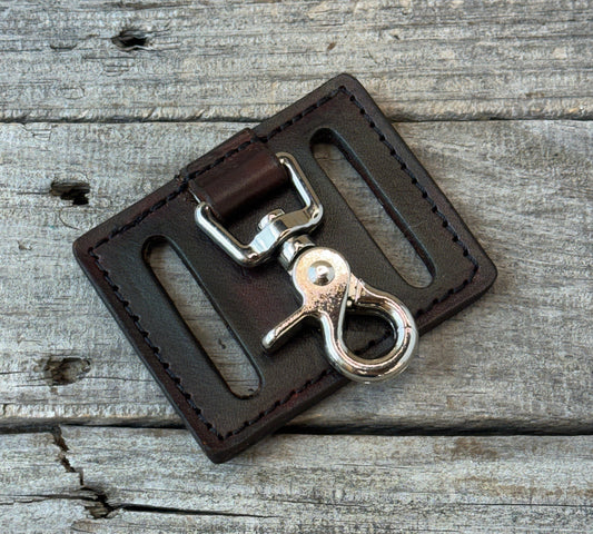 Brown leather key fob with silver clasp on a wooden surface