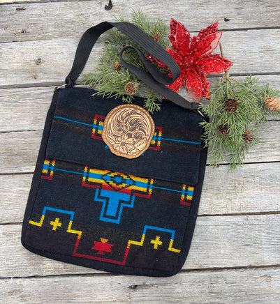 Black woven Southwest messenger bag with hand-tooled leather floral patch and yellow stitching, handmade by Cherokee Rose Custom Leather in East Texas.