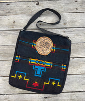 Black woven Southwest messenger bag with hand-tooled leather floral patch and yellow stitching, handmade by Cherokee Rose Custom Leather in East Texas.