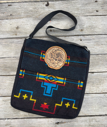 Black woven Southwest messenger bag with hand-tooled leather floral patch and yellow stitching, handmade by Cherokee Rose Custom Leather in East Texas.