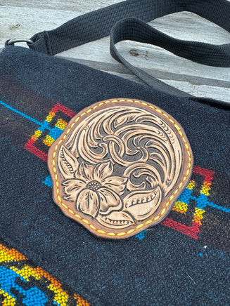 Black woven Southwest messenger bag with hand-tooled leather floral patch and yellow stitching, handmade by Cherokee Rose Custom Leather in East Texas.