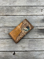 Brown leather wallet with intricate designs on a wooden surface