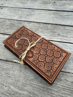 Brown leather wallet with embossed pattern on a wooden surface