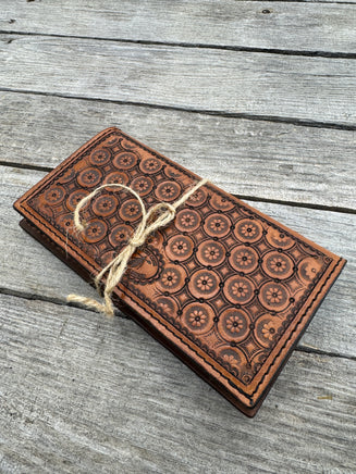 Brown leather wallet with embossed pattern on a wooden surface