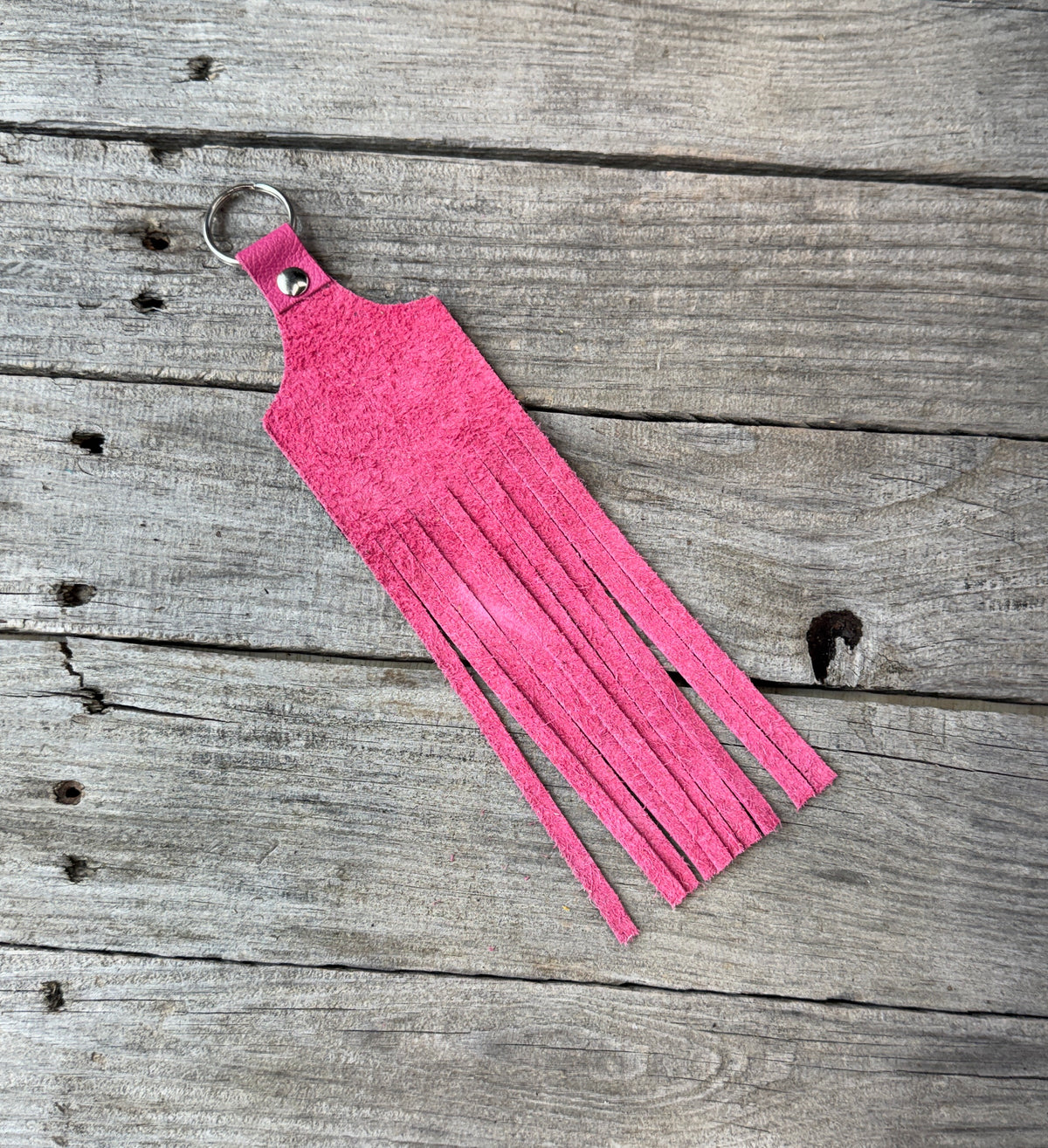 Pink fringed keychain on a wooden surface