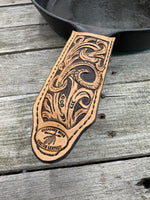Hand tooled leather cast iron skillet handle cover with floral scroll carving and dyed background, handmade by Cherokee Rose Custom Leather in East Texas.