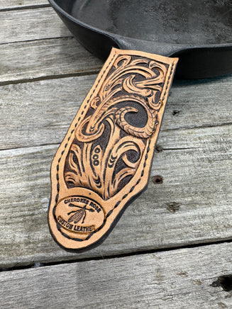 Hand tooled leather cast iron skillet handle cover with floral scroll carving and dyed background, handmade by Cherokee Rose Custom Leather in East Texas.
