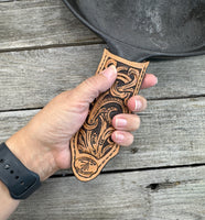 Hand tooled leather cast iron skillet handle cover with floral scroll carving and dyed background, handmade by Cherokee Rose Custom Leather in East Texas.