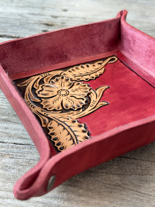 Custom leather valet tray with a hand carved floral design on a wooden surface