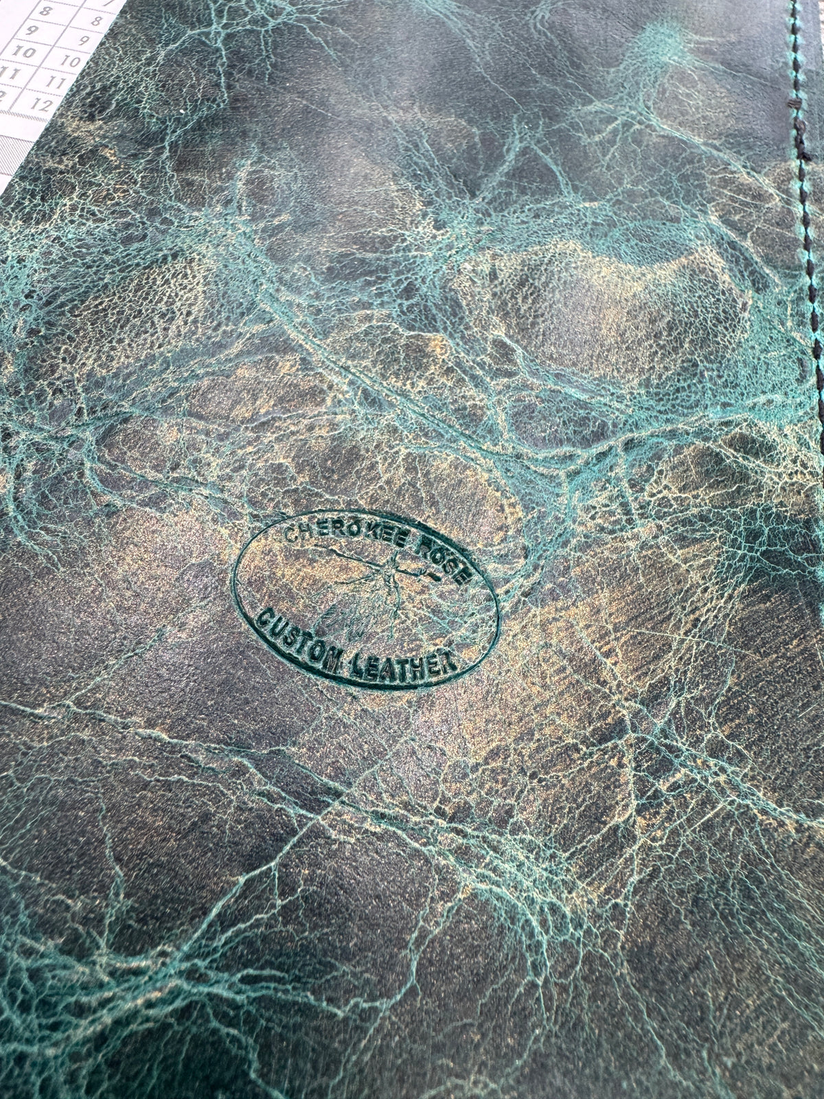Close-up of a leather product with a visible brand stamp on a textured surface.