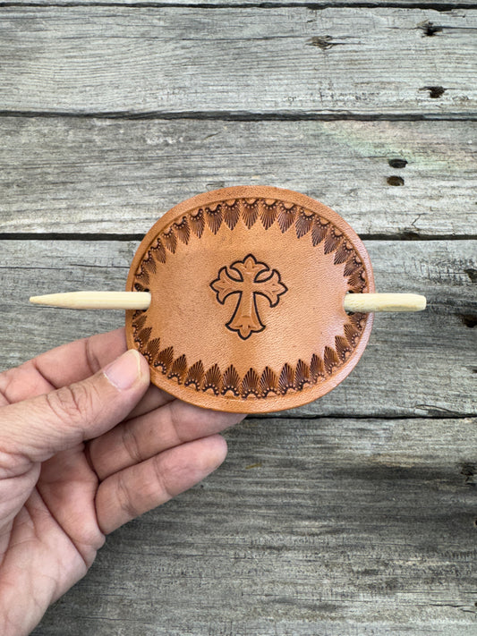 Hand stamped leather hair barrette with cross and sunburst border, oval shape with bamboo hair stick.