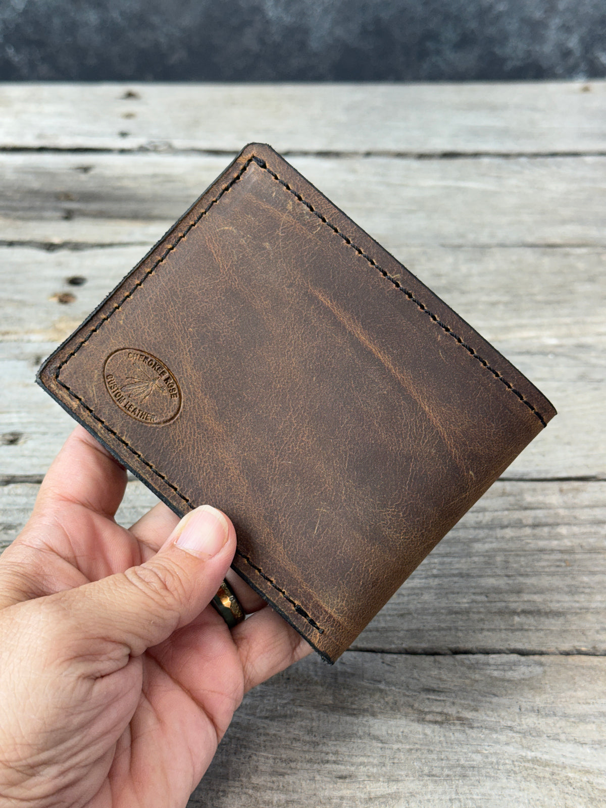 Dark brown full grain leather bifold wallet showing natural leather grain