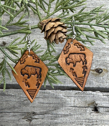Diamond-shaped light tan leather earrings with hand-stamped bison, arrows, and tribal geometric design, handmade by Cherokee Rose Custom Leather in East Texas.