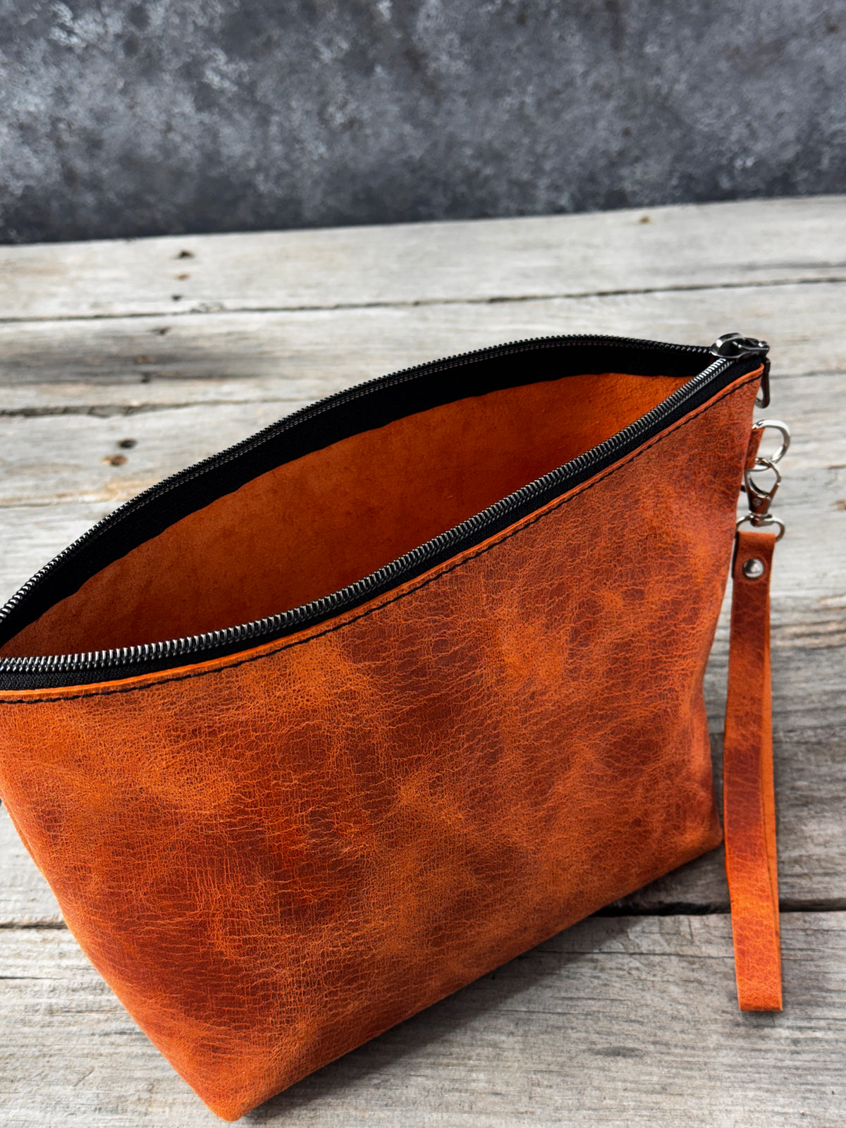 Large orange leather toiletry pouch with silver tone hardware and wristlet strap