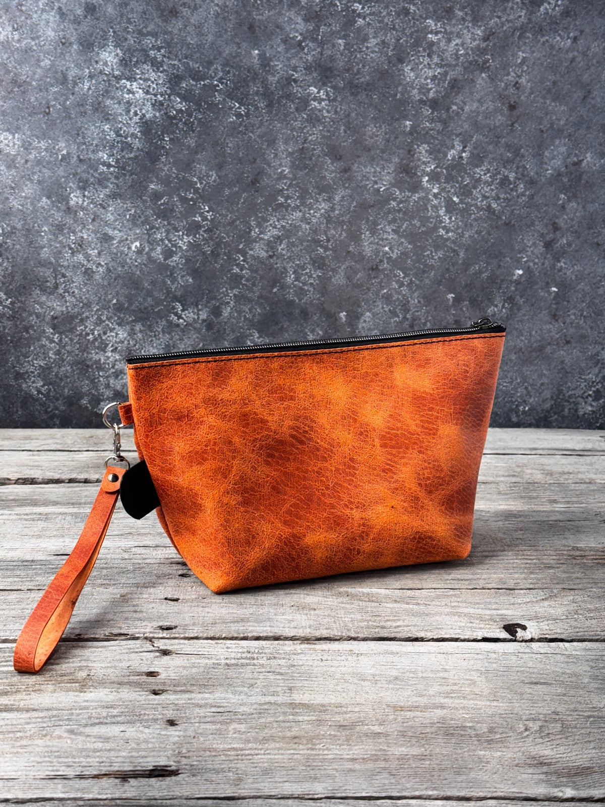 Large handmade distressed orange leather cosmetic bag with black zipper and detachable wristlet