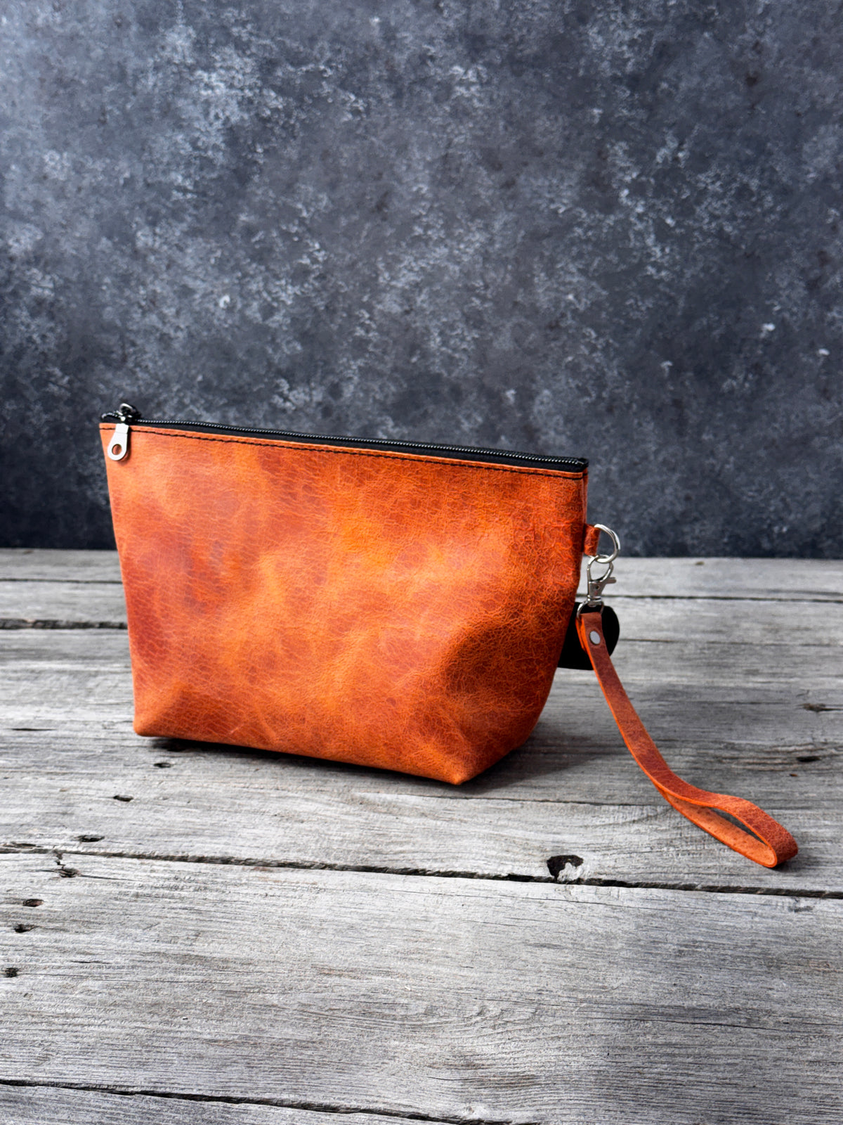 Handmade orange leather makeup travel pouch with black zipper closure