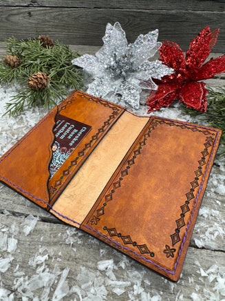 Hand-carved leather field notes cover with Western floral and feather design, purple and turquoise accents, handmade by Cherokee Rose Custom Leather.