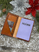 Hand-carved leather field notes cover with Western floral and feather design, purple and turquoise accents, handmade by Cherokee Rose Custom Leather.