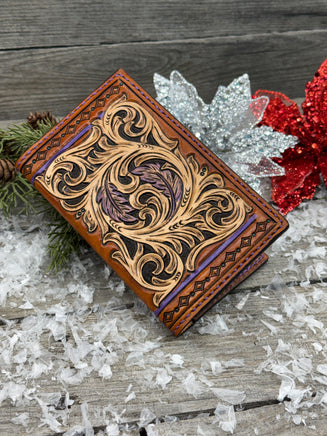 Hand-carved leather field notes cover with Western floral and feather design, purple and turquoise accents, handmade by Cherokee Rose Custom Leather.
