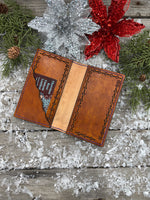 Hand-carved leather field notes cover with Western floral and feather design, purple and turquoise accents, handmade by Cherokee Rose Custom Leather.