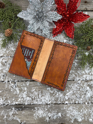 Hand-carved leather field notes cover with Western floral and feather design, purple and turquoise accents, handmade by Cherokee Rose Custom Leather.