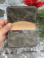 Hand-carved chocolate brown leather card wallet with floral scroll design and gray oil-tanned interior, handmade by Cherokee Rose Custom Leather.