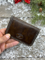 Hand-carved chocolate brown leather card wallet with floral scroll design and gray oil-tanned interior, handmade by Cherokee Rose Custom Leather.