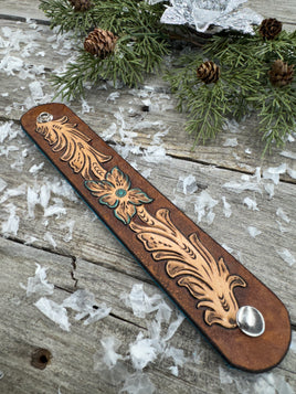 Hand-carved leather cuff bracelet with turquoise flower and floral scrollwork, silver snaps, turquoise suede back, handmade by Cherokee Rose Custom Leather in Texas.