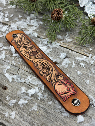 Hand-carved leather cuff bracelet with pink flower accent, gunmetal snaps, and brown suede lining, handmade by Cherokee Rose Custom Leather in Texas.