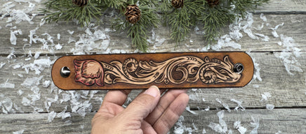 Hand-carved leather cuff bracelet with pink flower accent, gunmetal snaps, and brown suede lining, handmade by Cherokee Rose Custom Leather in Texas.