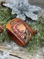 Hand-carved leather cuff bracelet with pink flower accent, gunmetal snaps, and brown suede lining, handmade by Cherokee Rose Custom Leather in Texas.