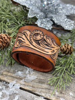 Hand-carved leather cuff bracelet with pink flower accent, gunmetal snaps, and brown suede lining, handmade by Cherokee Rose Custom Leather in Texas.